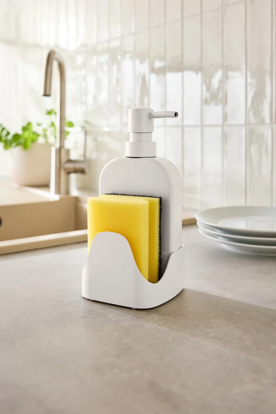 Sur un comptoir de cuisine, un distributeur de savon avec une éponge jaune.