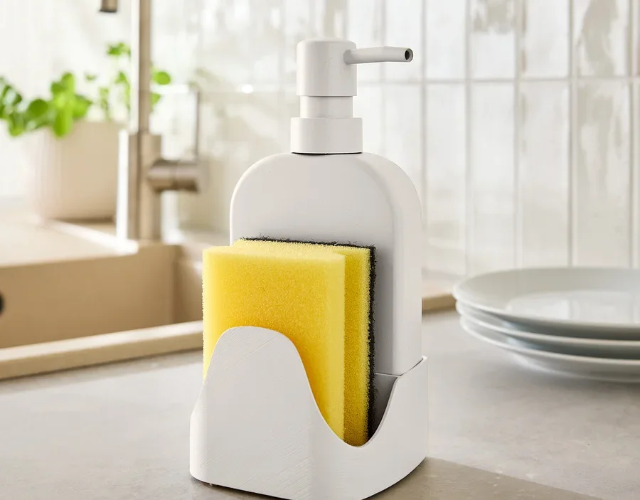 Sur un comptoir de cuisine, un distributeur de savon avec une éponge jaune.