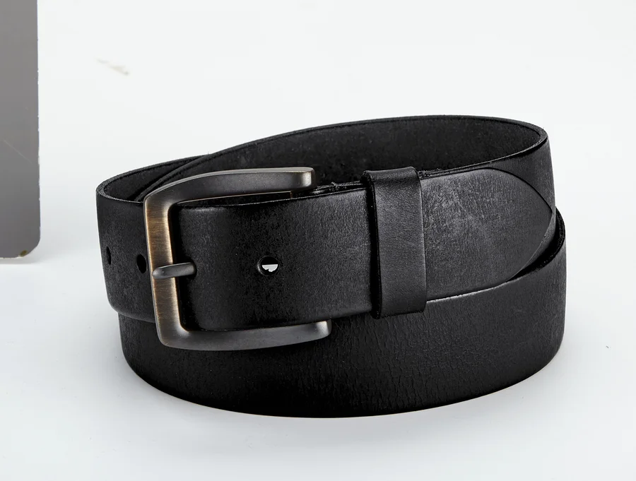 Une ceinture en cuir noire avec une boucle en métal est enroulée sur une surface claire.