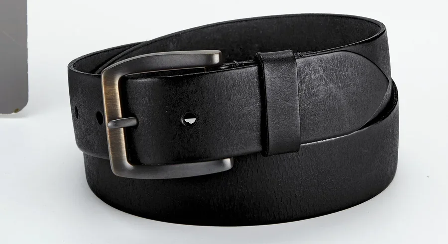 Une ceinture en cuir noire avec une boucle en métal est enroulée sur une surface claire.