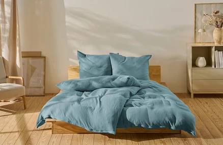 Parure de lit en mousseline bleue de taille standard et grande taille sur un lit.