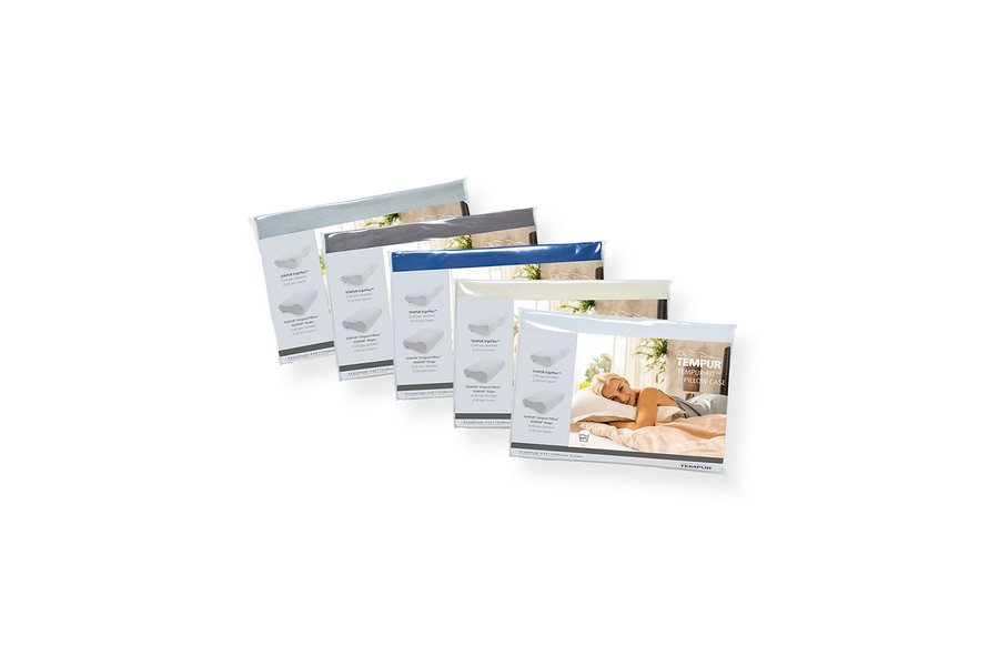 Fünf verpackte TEMPUR Kissenbezüge, diagonal angeordnet, in Hellblau, Dunkelgrau, Blau, Creme und Pfirsichfarben. Die vorderste pfirsichfarbene Verpackung zeigt eine blonde Frau, die auf einem Kissen schläft.