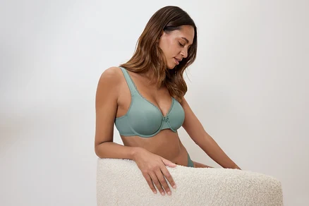 Une femme est assise et porte un soutien-gorge vert clair.