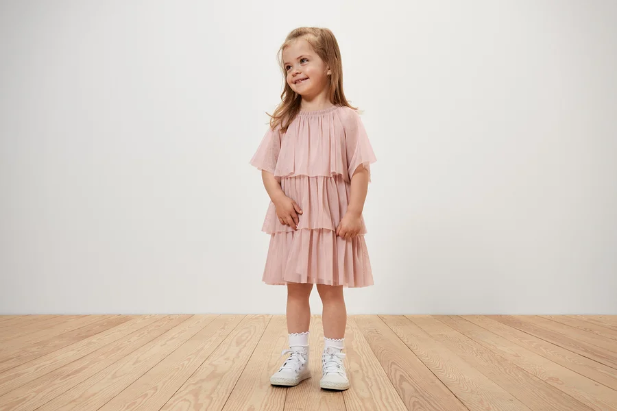 Une fillette souriante porte une robe en tulle pour enfant.