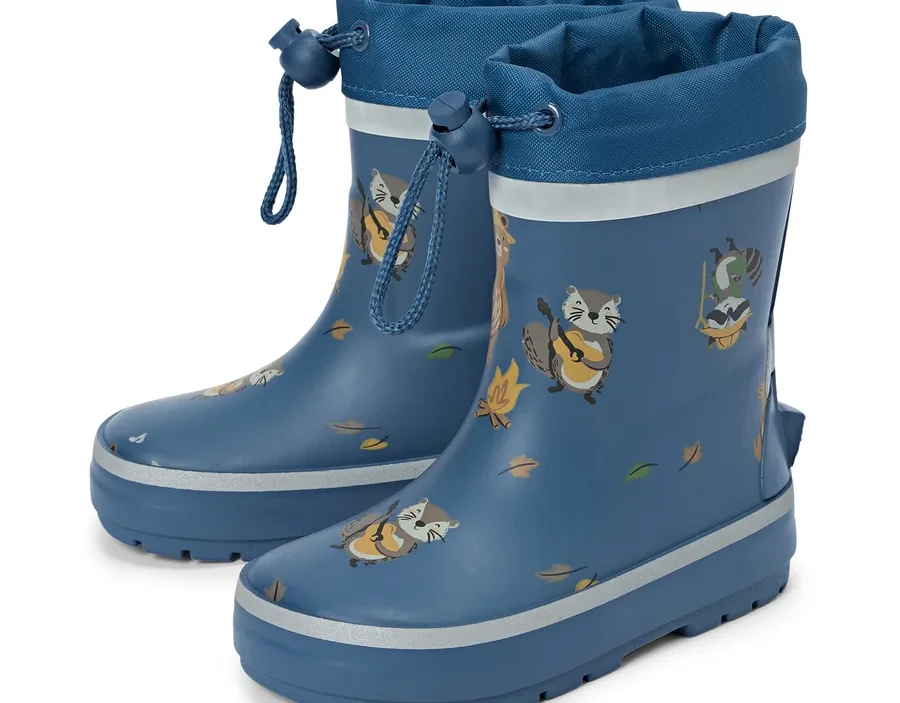 Une paire de bottes en caoutchouc bleues avec cordon de serrage et motifs de raton laveur se tient sur un fond blanc.