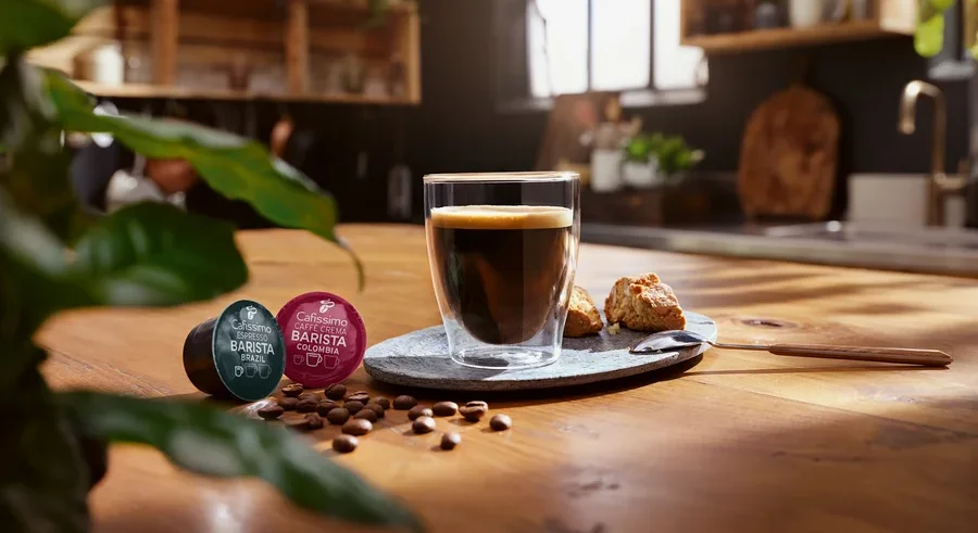 Une tasse de café est posée sur une table à côté de deux capsules Cafissimo Barista.