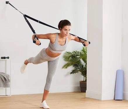 Femme s'exerçant avec des sangles de suspension.