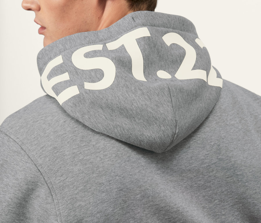 Homme portant un sweat-shirt à capuche gris.
