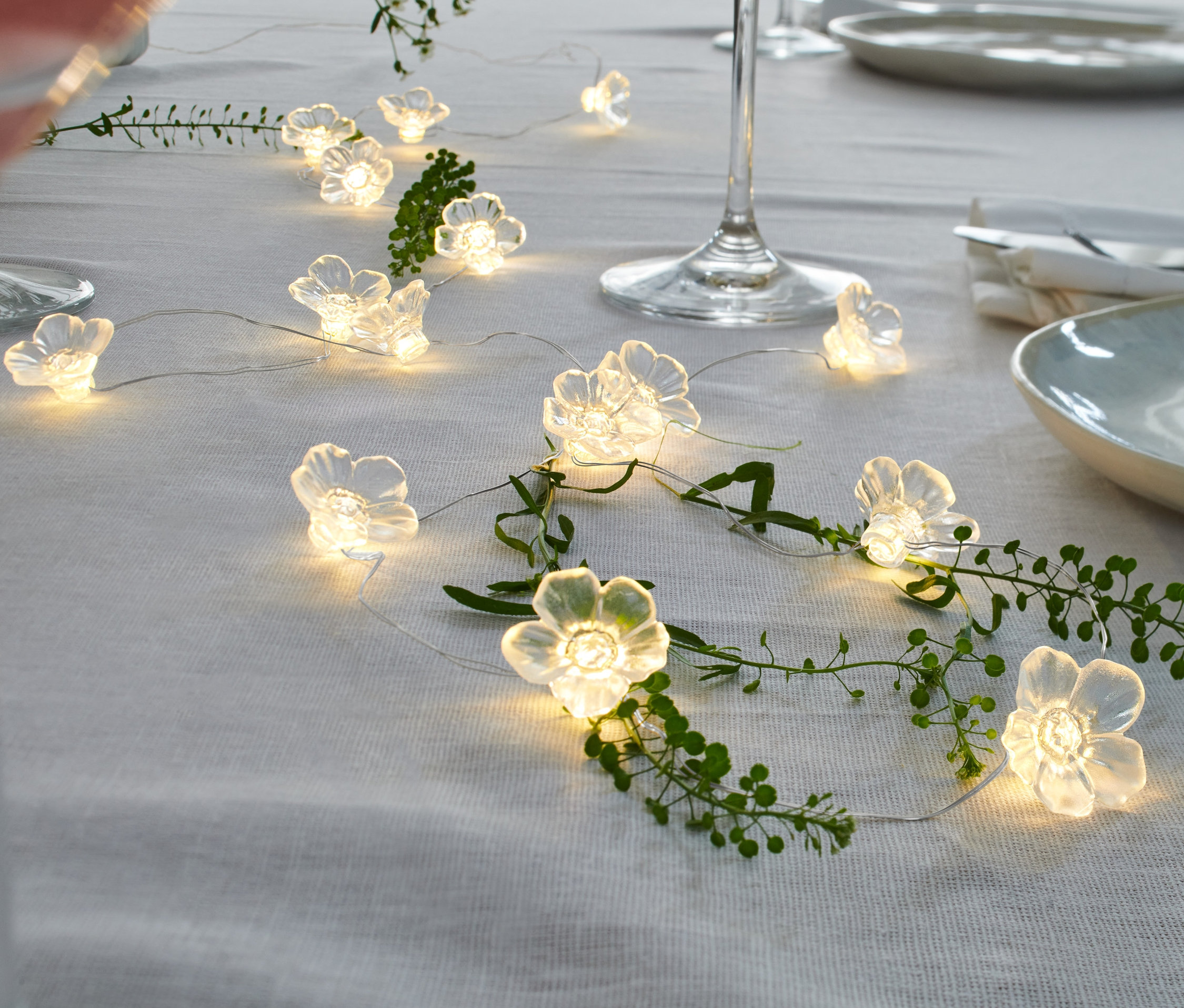 Une micro-guirlande lumineuse à LED en forme de fleurs est disposée sur une table de manière décorative.