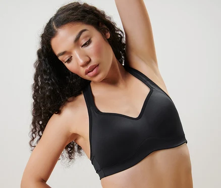 Femme s'étirant dans un soutien-gorge de sport noir.