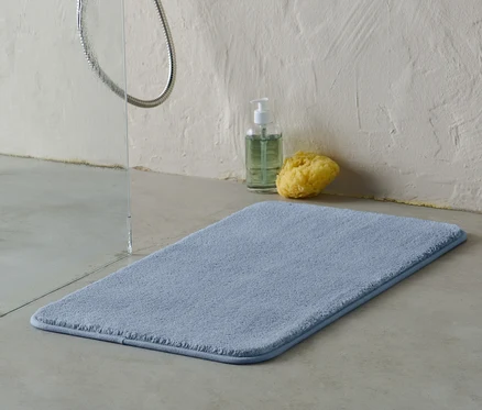 Un tapis de bain bleu, env. 70 x 40 cm, est posé sur le sol de la salle de bain.