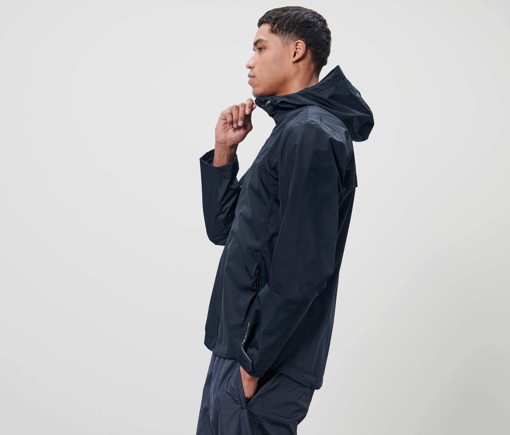 Homme fermant une veste de pluie unisexe bleue.