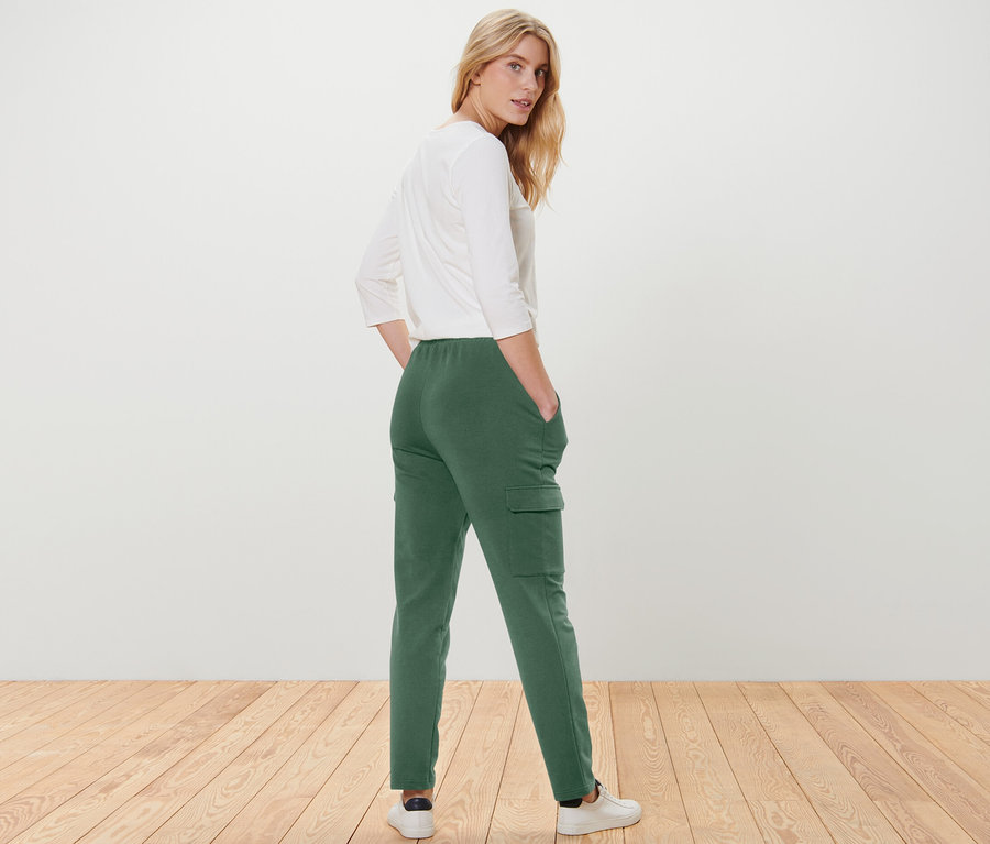 Une femme regardant par-dessus son épaule pose en pantalon de jogging vert avec poches cargo.