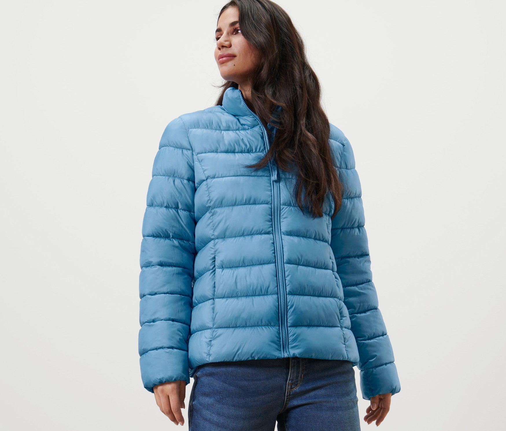 Une femme porte une veste matelassée et un jean.