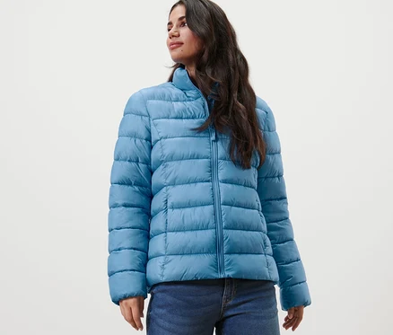 Une femme porte une veste matelassée et un jean.