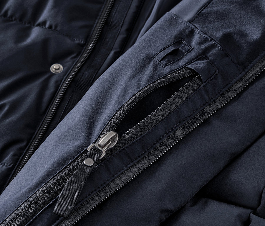 Détail d'une parka matelassée bleu marine avec capuche, fermeture éclair et boutons.