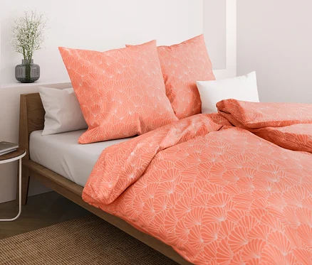 Gros plan d'un lit avec des parures de lit corail en microfibre avec coquillages, taille standard et grande taille.