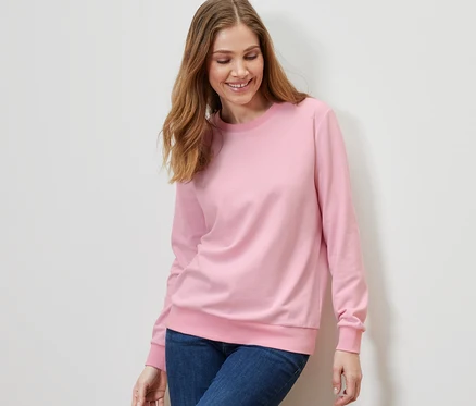 Femme portant un sweat-shirt rose et un jean.