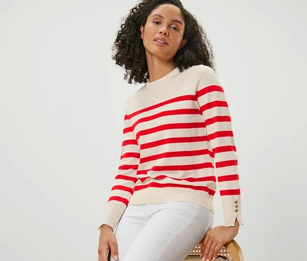 Femme assise sur une chaise portant un pull en maille fine rayé rouge.