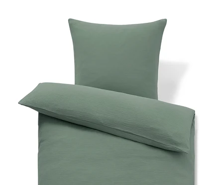Parure de lit en mousseline verte, avec une housse de couette à plat et une taie d'oreiller posée horizontalement dessus.