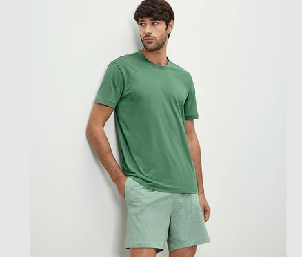 Homme appuyé contre un mur portant un ensemble pyjama shorty.
