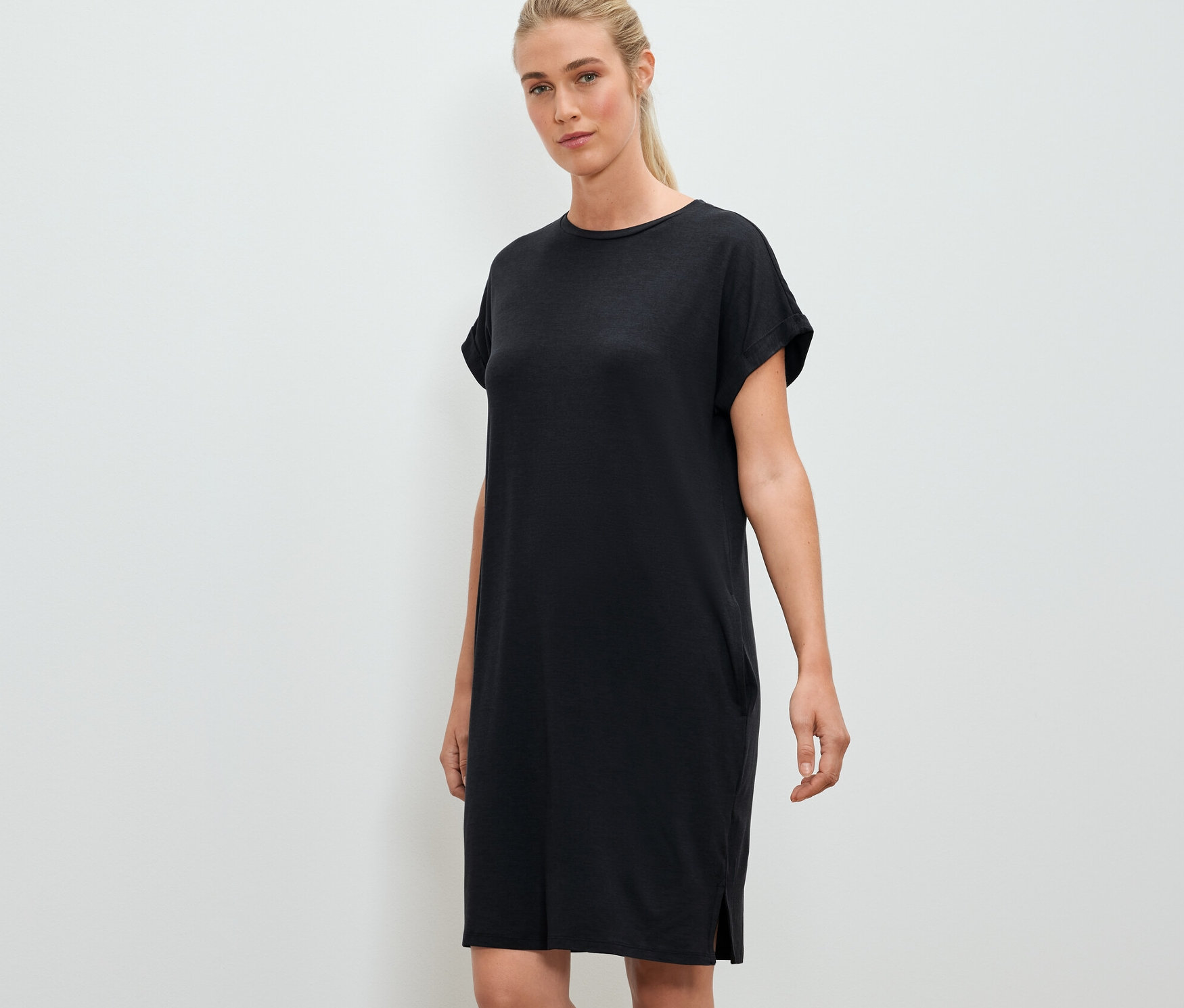 Une femme pose et porte une robe d'extérieur noire.