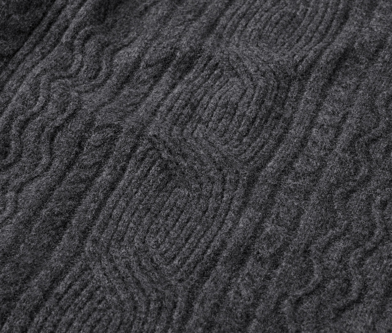 Gros plan sur le motif tricoté d'un pull gris.