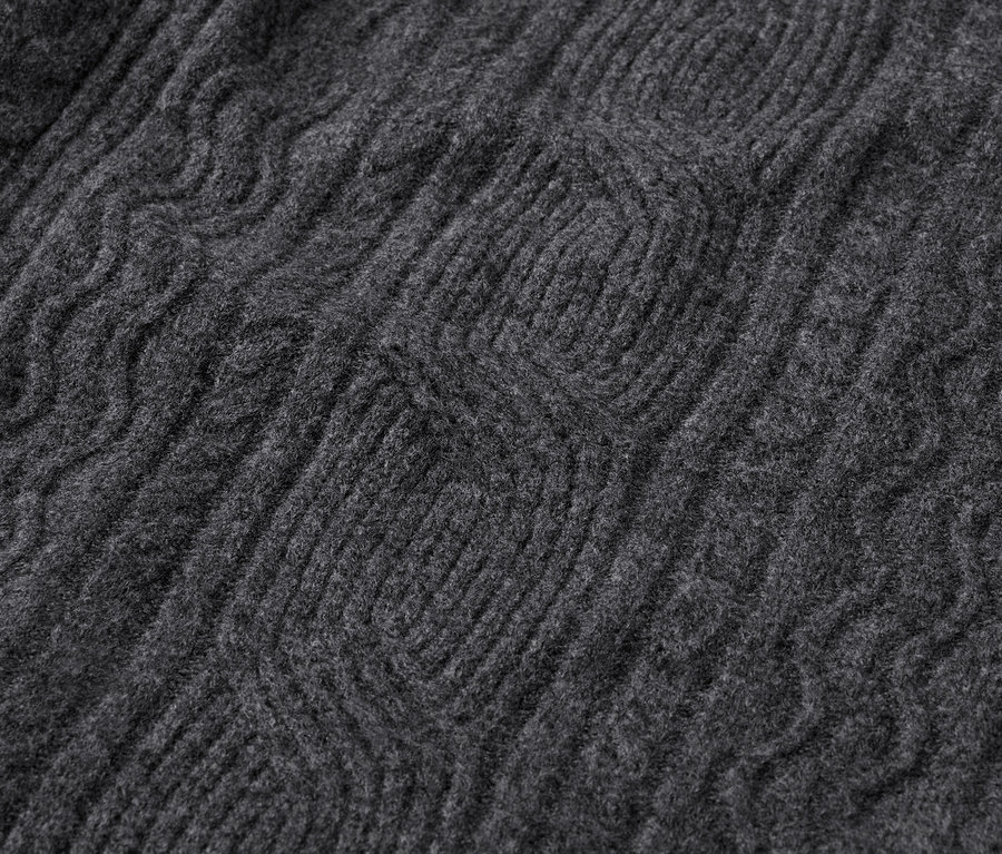 Gros plan sur le motif tricoté d'un pull gris.