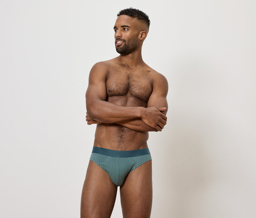 Un homme les bras croisés portant un slip vert.