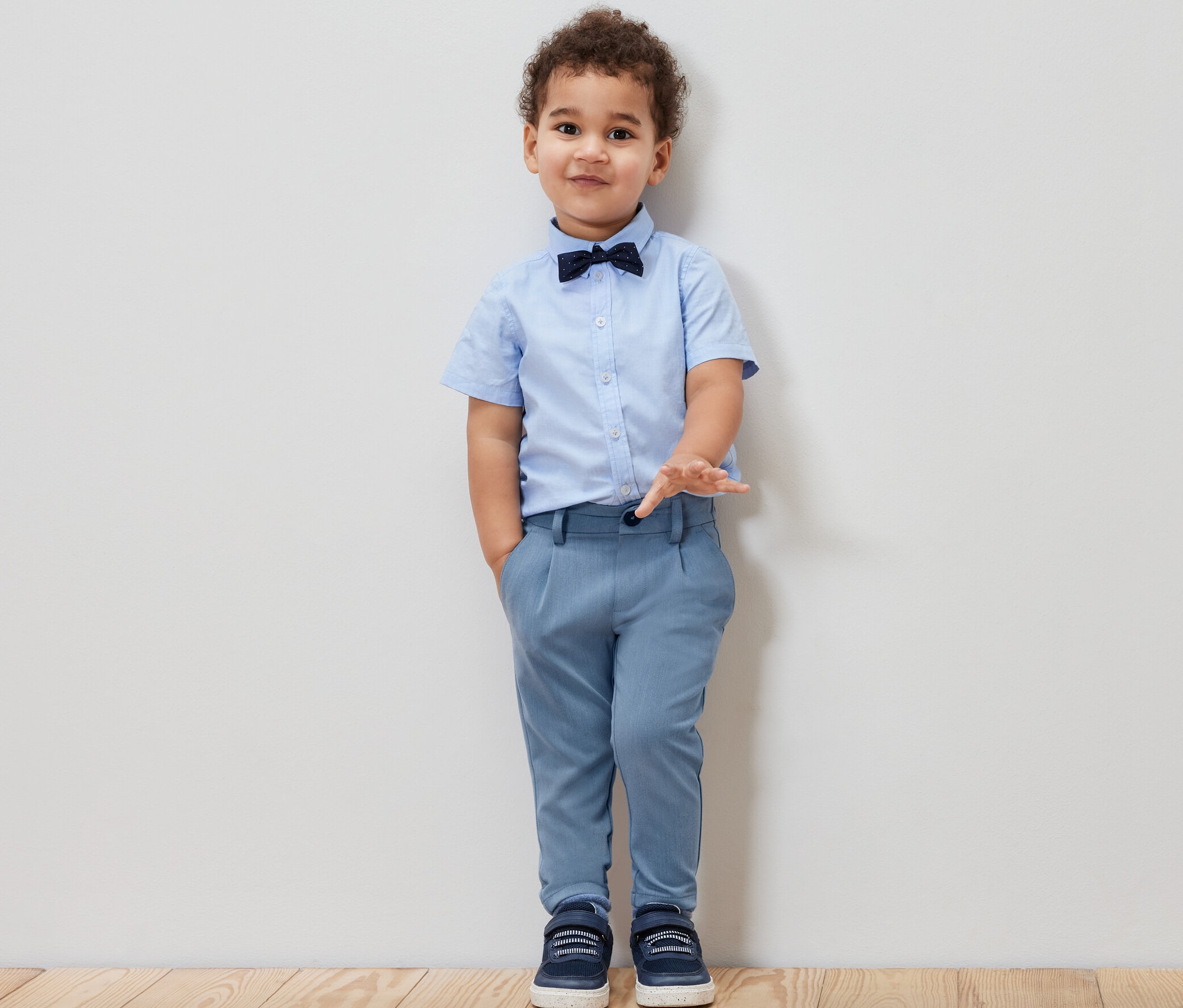 Garçon portant une chemise bleue, un nœud papillon et un pantalon chino pour enfant.
