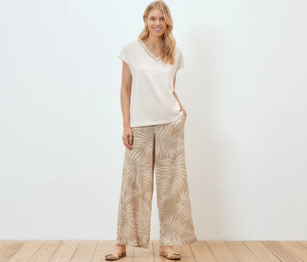 Une femme debout porte un pantalon palazzo structuré avec un imprimé intégral.