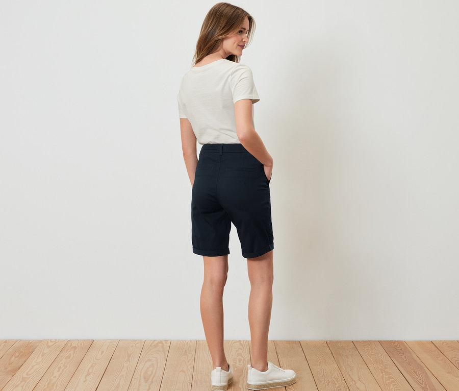 Une femme, vue de dos, porte un short chino bleu marine.