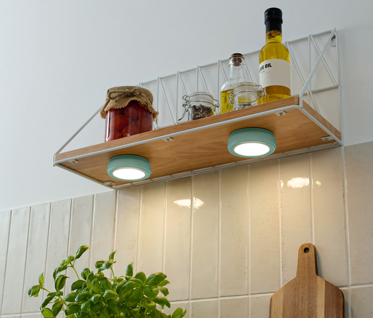 Sur une étagère se trouvent des bocaux de stockage et des bouteilles d'huile, dont deux 2 LED-Multifunktionsleuchten turquoise.