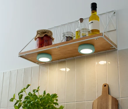 Sur une étagère se trouvent des bocaux de stockage et des bouteilles d'huile, dont deux 2 LED-Multifunktionsleuchten turquoise.
