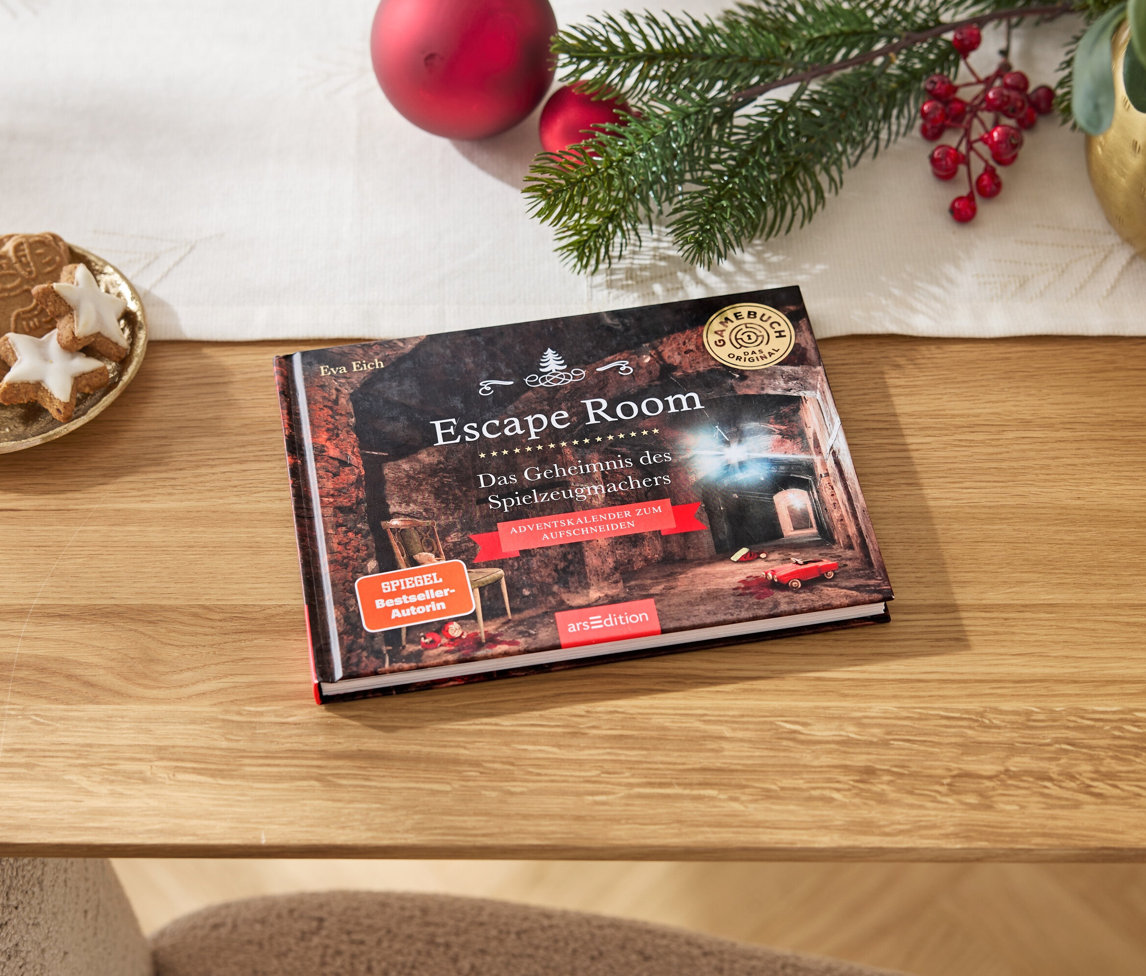 Un livre Escape Room est posé sur une table en bois à côté d'une assiette de pain d'épices et de décorations de Noël.