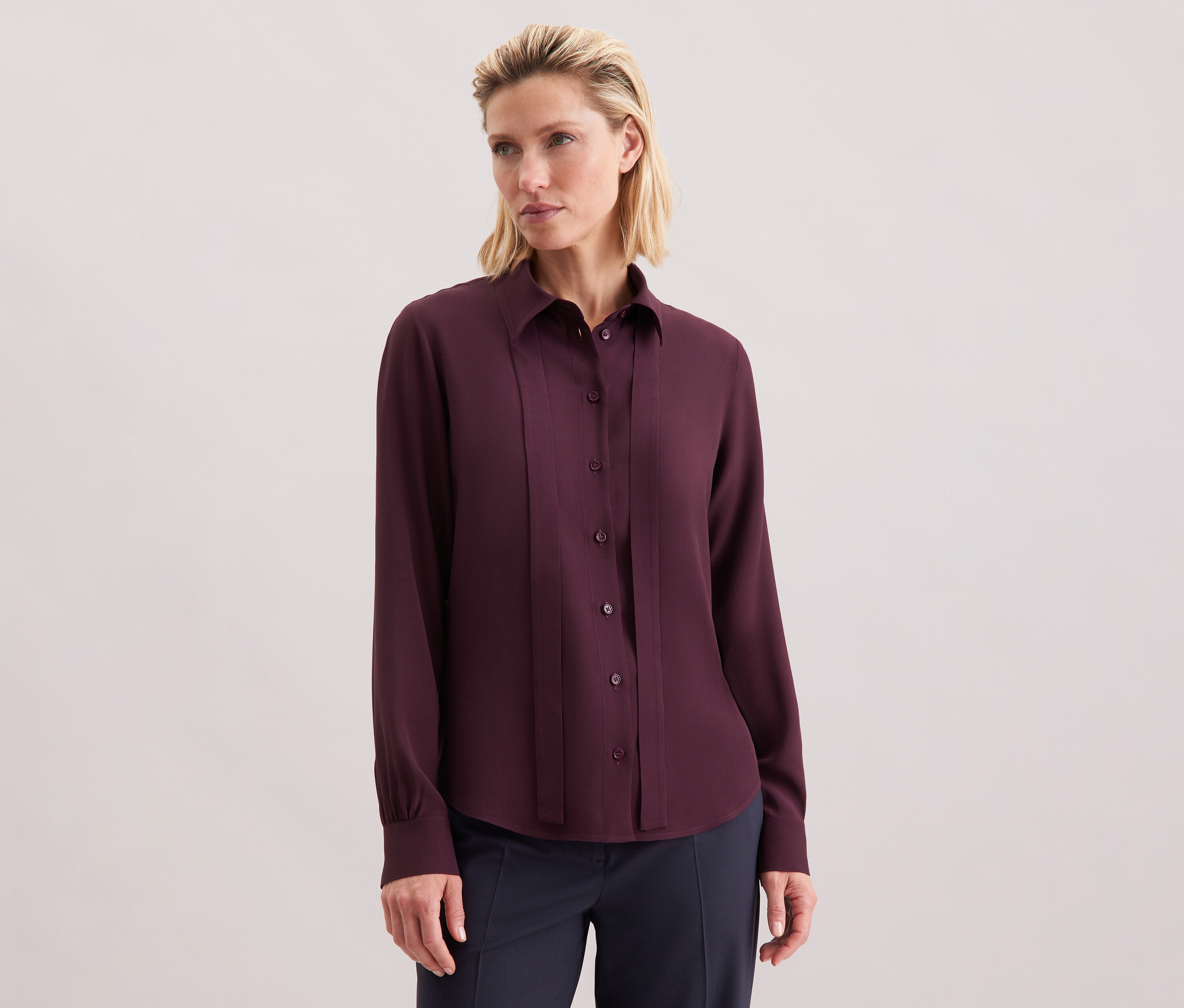 Femme portant un chemisier à col lavallière en viscose Seidensticker, bordeaux, avec des boutons.