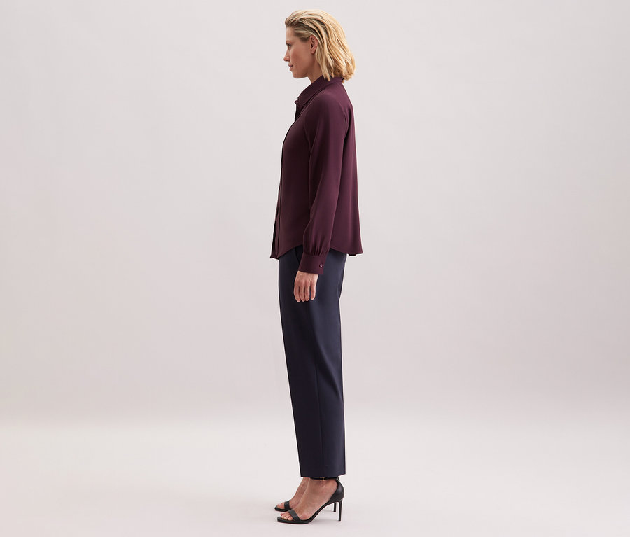 Femme portant un chemisier à col lavallière en viscose Seidensticker, un pantalon foncé et des sandales noires.