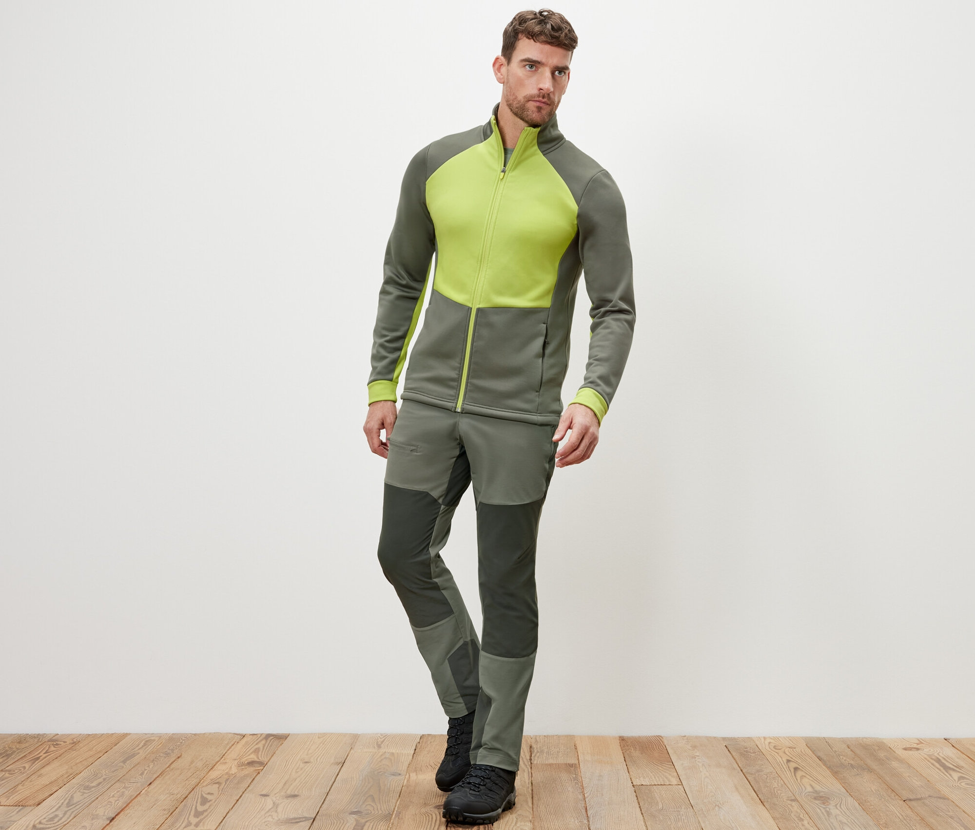 Un homme pose en veste thermique et pantalon.