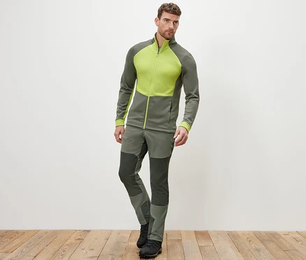 Un homme pose en veste thermique et pantalon.