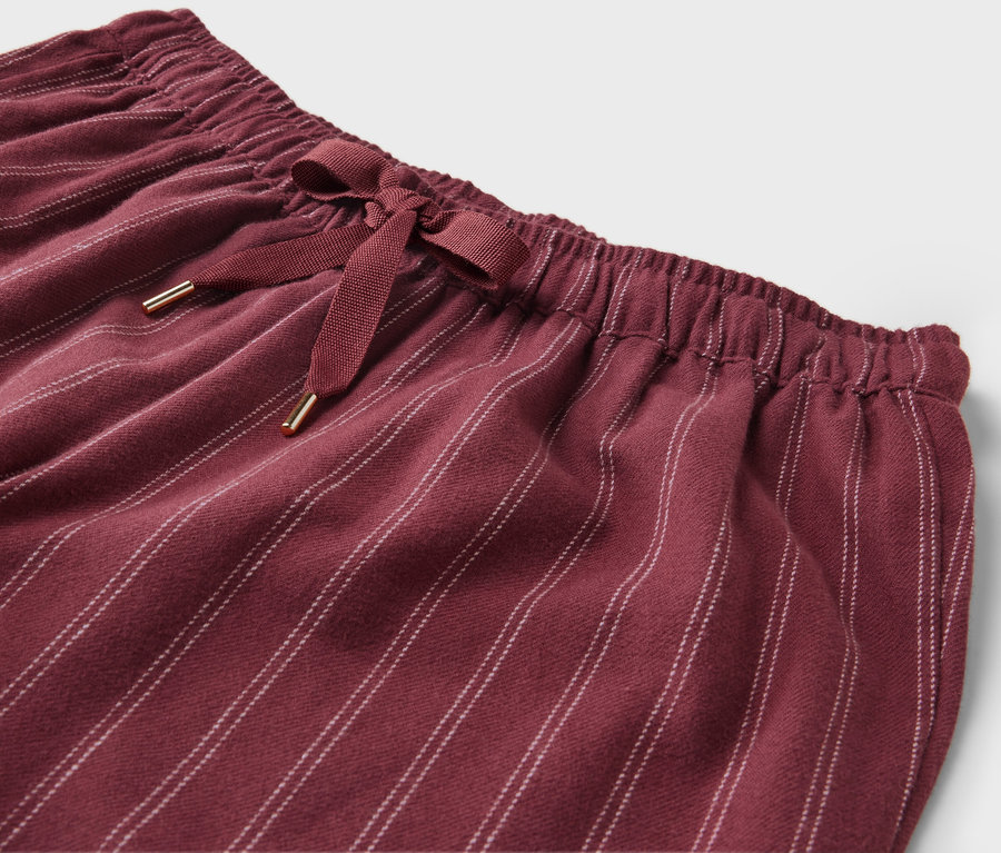 Gros plan d'un pantalon bordeaux rayé avec un nœud à la taille.