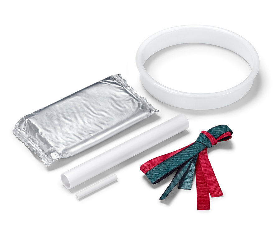 Un emballage argenté, un cercle blanc, deux bâtons blancs et un ruban rouge et vert sur fond blanc.