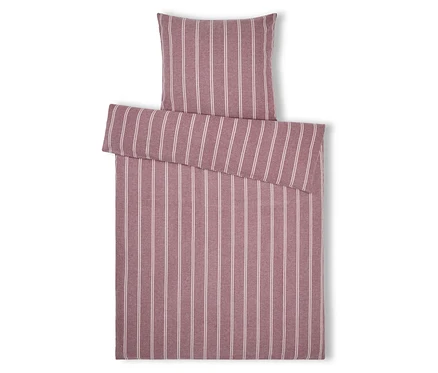 Linge de lit rayé avec oreiller dans les tons rose et blanc, posé sur un fond blanc.