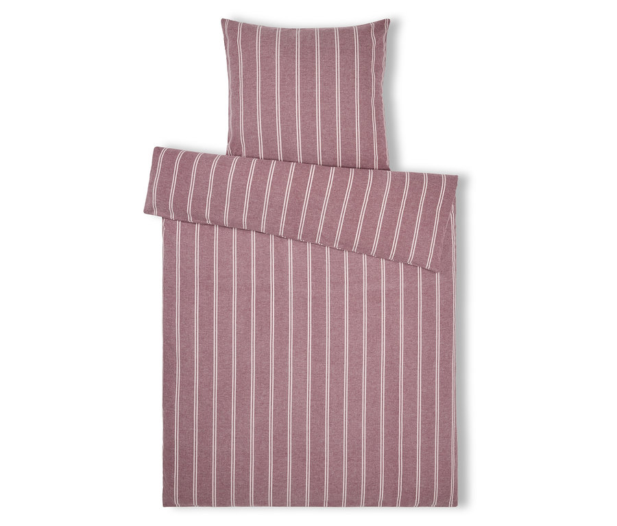 Linge de lit rayé avec oreiller dans les tons rose et blanc, posé sur un fond blanc.