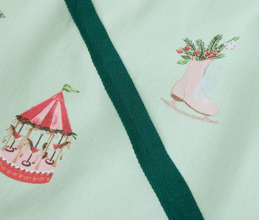 Tissu vert clair imprimé avec un carrousel, des patins à glace avec des fleurs et une maison en pain d'épice.