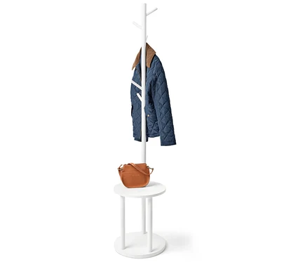 Sur un porte-manteau blanc se trouvent une veste matelassée bleue et un sac à main marron.
