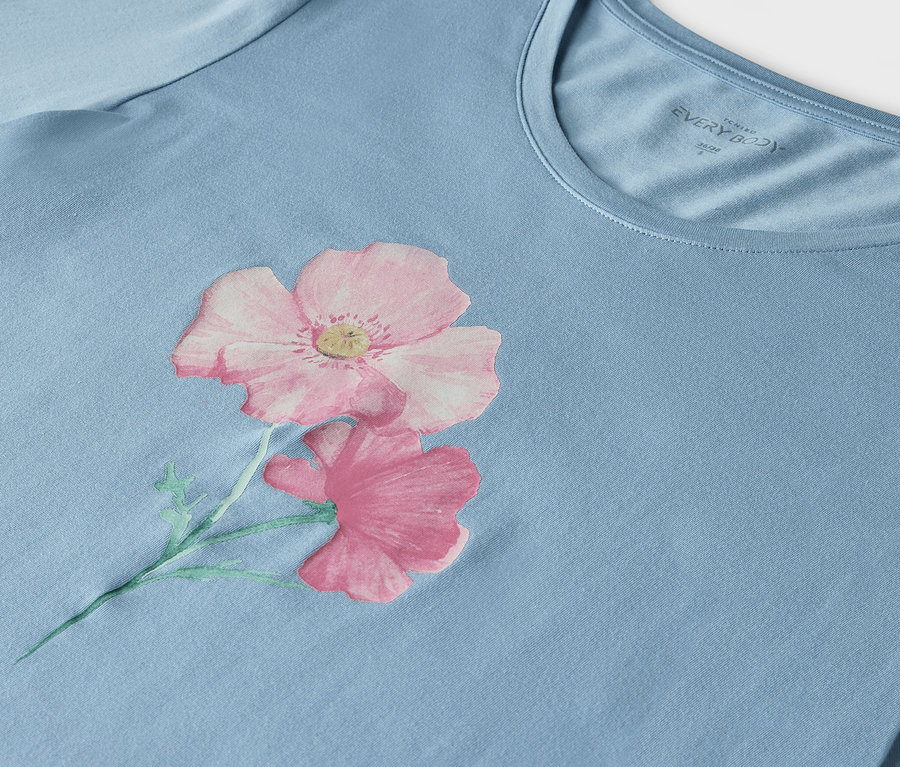 Détail d'un t-shirt bleu clair avec un imprimé de deux fleurs roses.