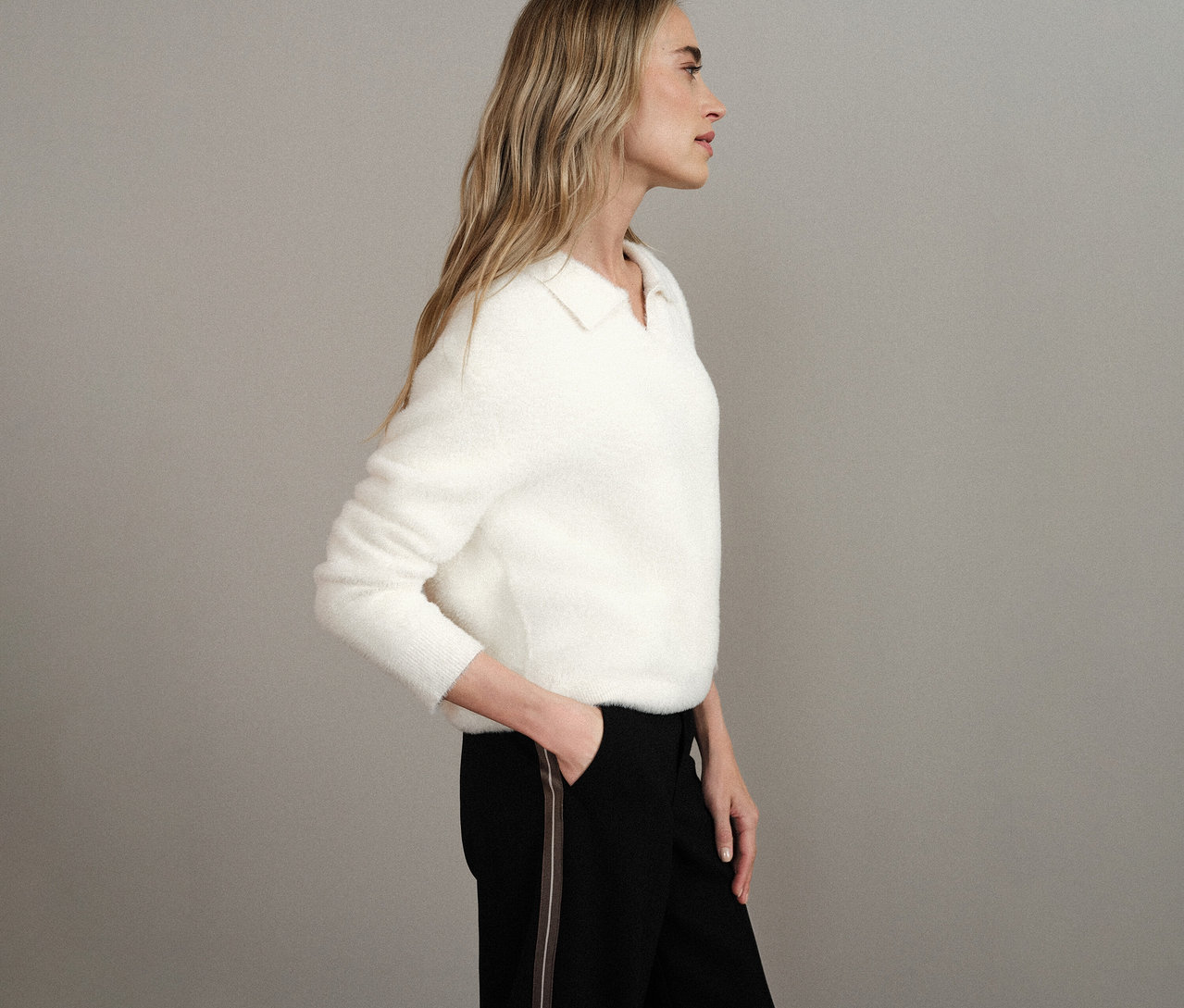 Femme de profil portant un pull en maille à col polo Street One blanc et un pantalon noir.