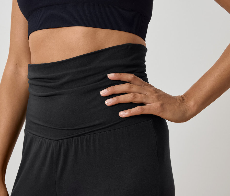 Femme posant dans un haut de sport noir et un pantalon taille haute.
