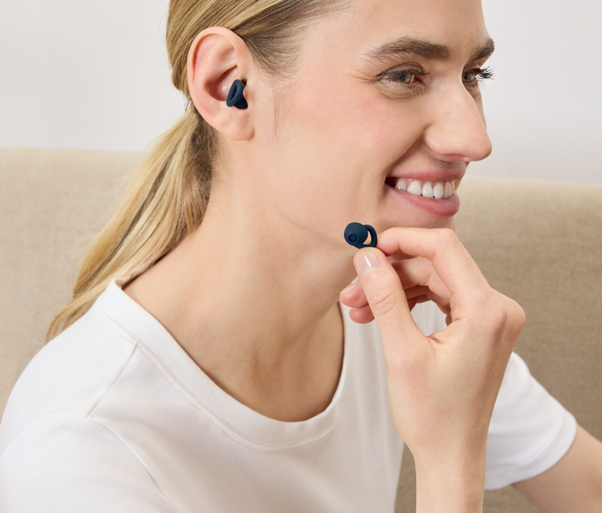 Une femme met un écouteur sans fil bleu foncé dans son oreille.