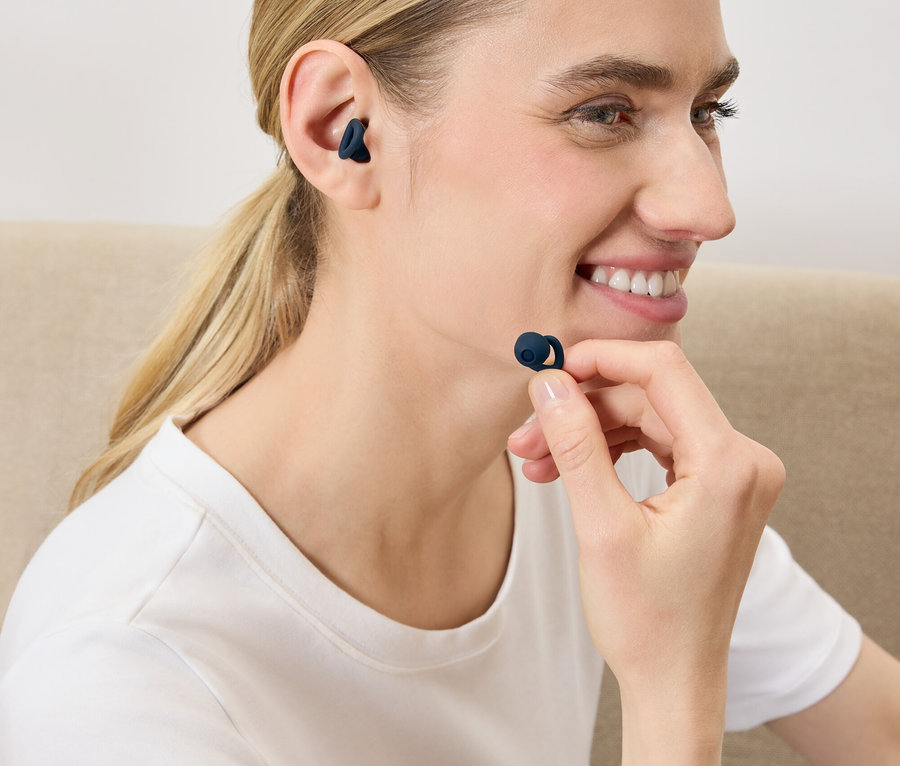 Une femme met un écouteur sans fil bleu foncé dans son oreille.